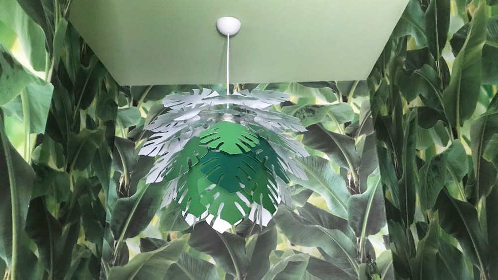 Zimmer mit grün gestrichener Decke, grüner Lampe und grüner Pflanzentapete